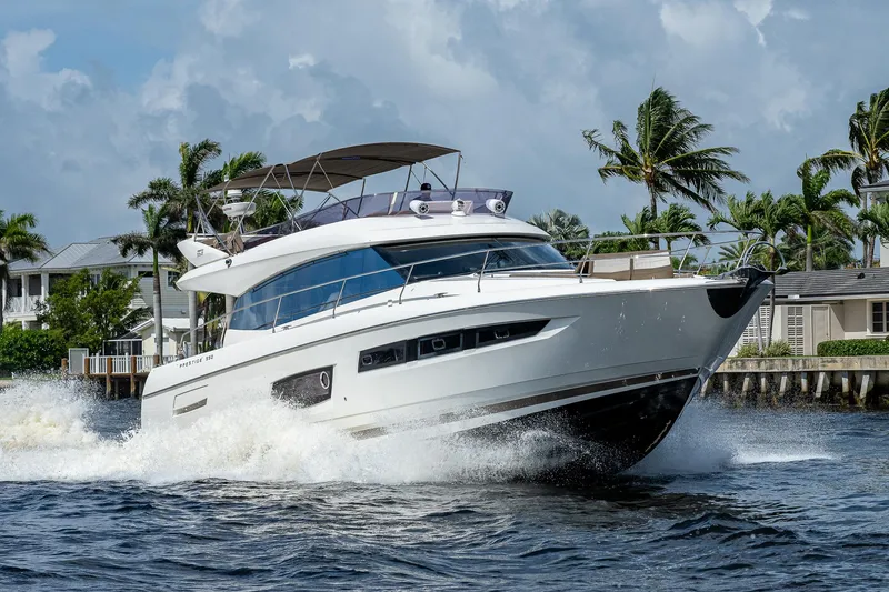 Slide: The Image of Luxury 2014 Prestige 550 yacht cruising on water, surrounded by palm trees and waterfront homes. - 33