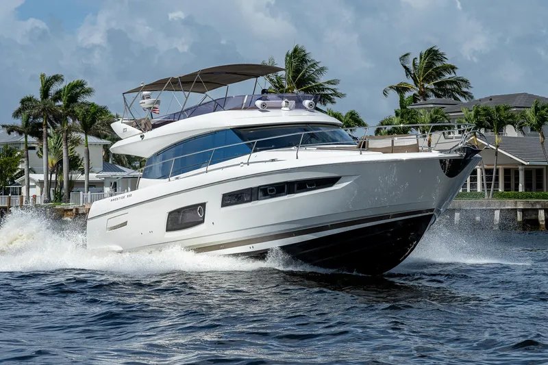Slide: The Image of Luxurious 2014 Prestige 550 yacht cruising on water with palm trees in the background. - 34