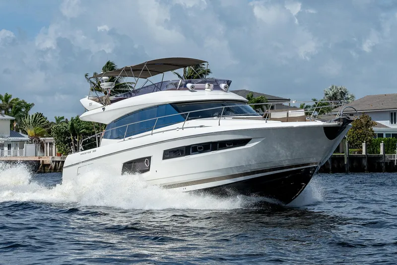 Slide: The Image of 2014 Prestige 550 yacht cruising on water with scenic background. - 35