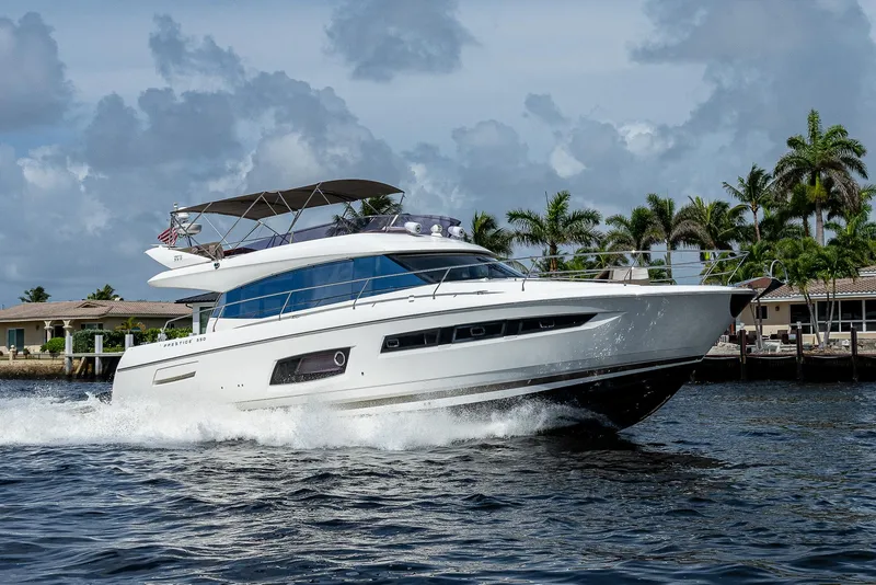 Slide: The Image of 2014 Prestige 550 yacht cruising on water with palm trees in the background. - 37