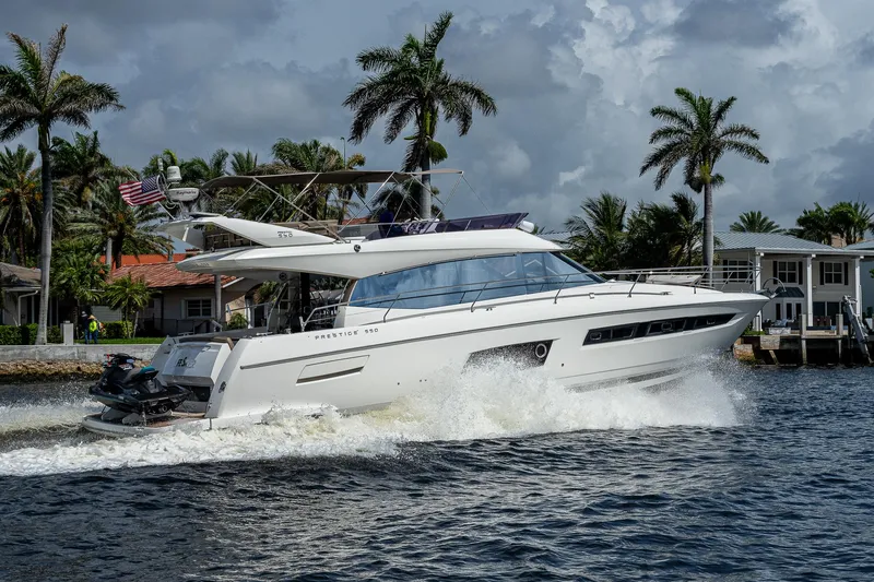 Slide: The Image of 2014 Prestige 550 yacht cruising on a tropical waterway with palm trees in the background. - 43