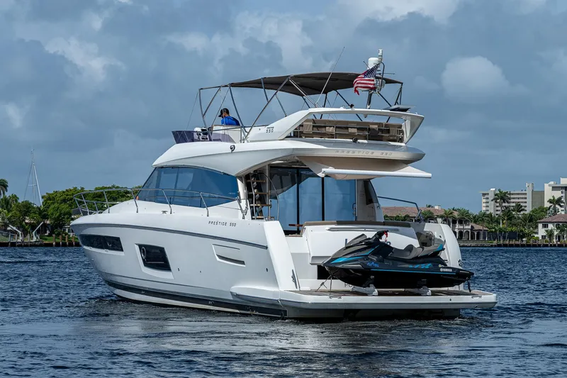 Slide: The Image of 2014 Prestige 550 yacht on water with jet ski, American flag, and scenic background. - 5