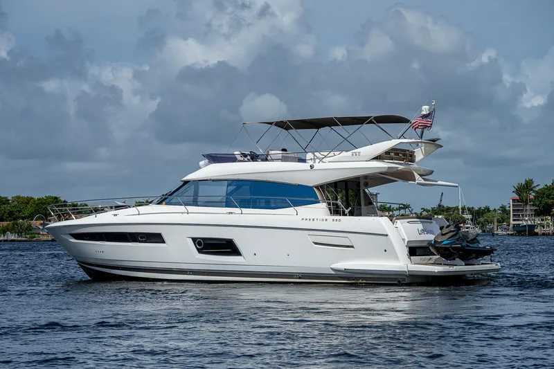 Slide: The Image of 2014 Prestige 550 yacht cruising on a calm waterway under a cloudy sky. - 8