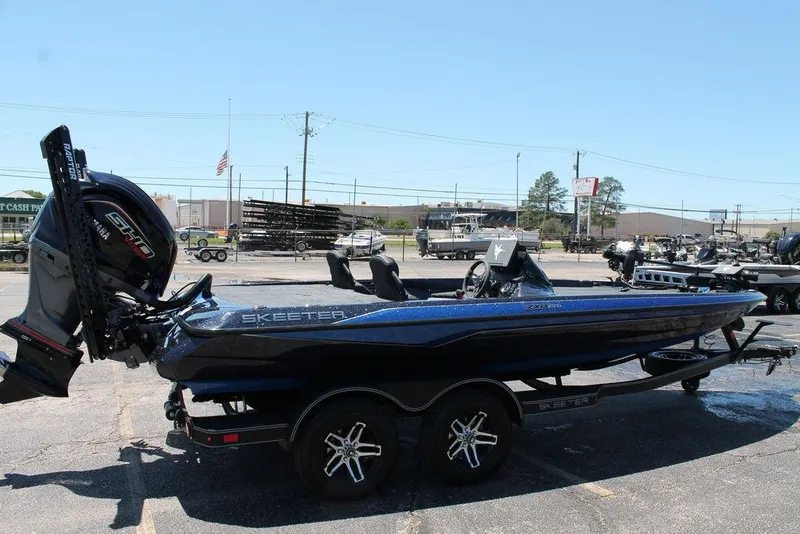 Slide: The Image of 2025 Skeeter ZXR20 bass boat with powerful engine, parked outdoors on a sunny day. - 2