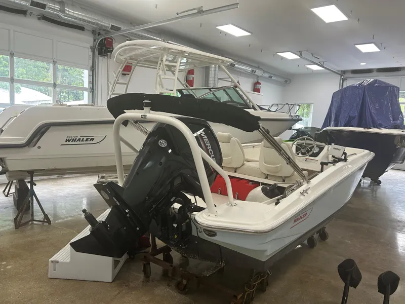 Slide: The Image of 2020 Boston Whaler 160 Super Sport boat in a showroom, featuring a powerful outboard motor. - 2