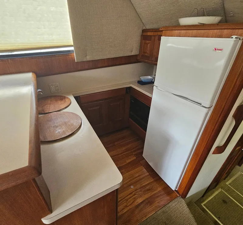 Slide: The Image of Compact kitchen in a 1991 Viking 45 Convertible boat with wood cabinetry and white appliances. - 12