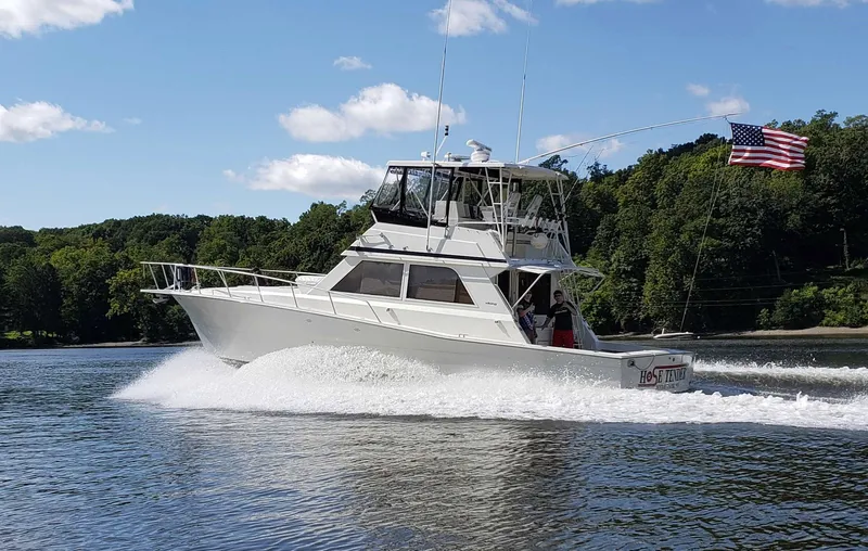 Slide: The Image of 1991 Viking 45 Convertible yacht cruising on a lake with American flag, surrounded by trees. - 2