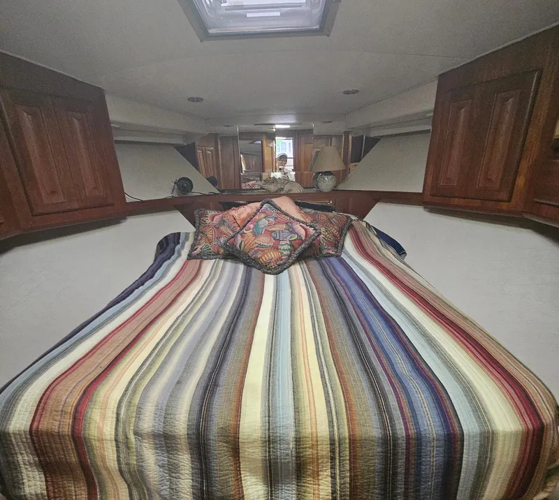 Slide: The Image of Cozy cabin interior of 1991 Viking 45 Convertible with striped bedding and wooden cabinets. - 20