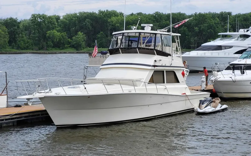 Slide: The Image of 1991 Viking 45 Convertible yacht docked by a river with lush greenery. - 27