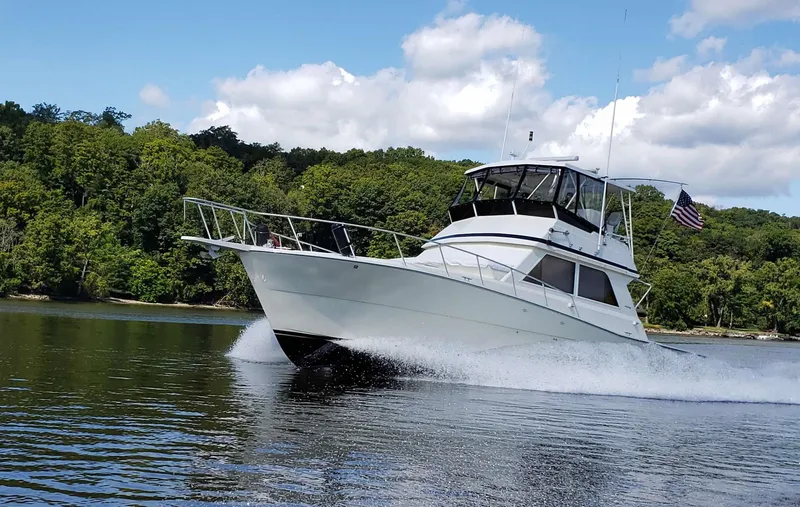 Slide: The Image of 1991 Viking 45 Convertible yacht cruising on a lake with lush green trees. - 3