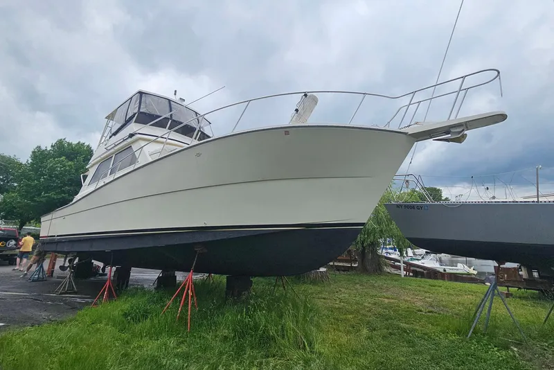 Slide: The Image of 1991 Viking 45 Convertible boat on land, supported by stands, under cloudy sky. - 43