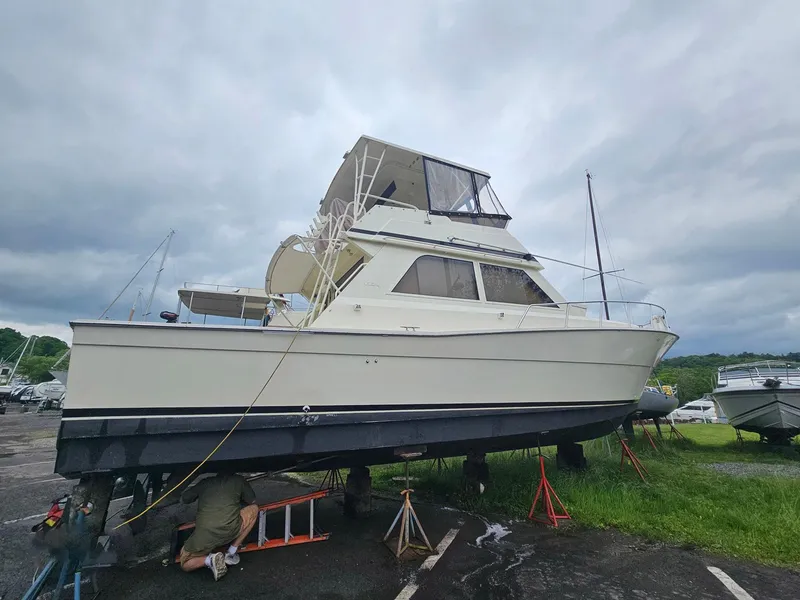 Slide: The Image of 1991 Viking 45 Convertible yacht on land, undergoing maintenance under cloudy skies. - 47