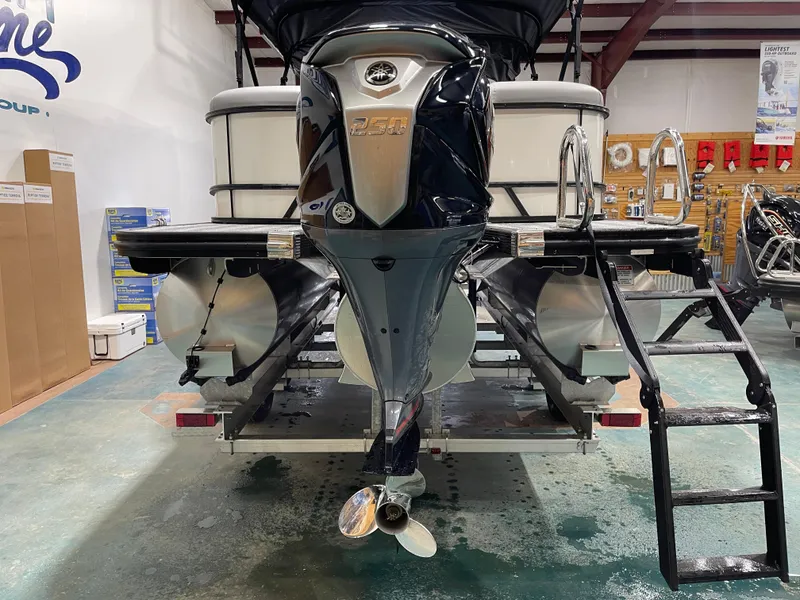 Slide: The Image of 2025 Bennington 25SSRSE pontoon boat in showroom, rear view with motor and ladder. - 10