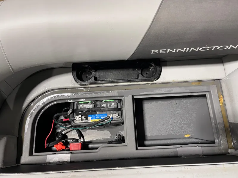 Slide: The Image of 2025 Bennington 25SSRSE boat battery compartment with visible wiring and storage area. - 16