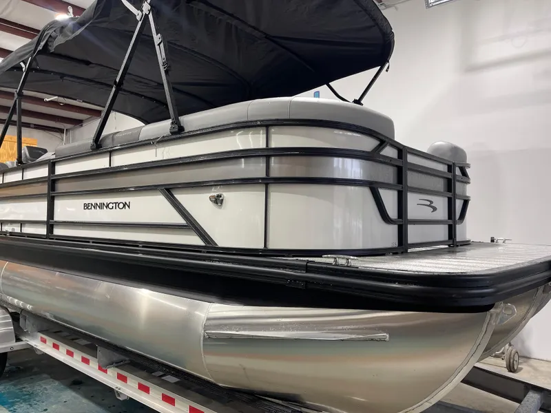 Slide: The Image of 2025 Bennington 25SSRSE pontoon boat with black canopy in a showroom. - 3