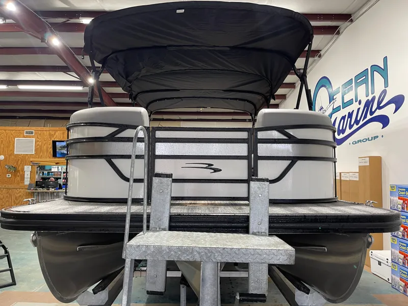 Slide: The Image of 2025 Bennington 25SSRSE pontoon boat in showroom, featuring sleek design and canopy. - 5