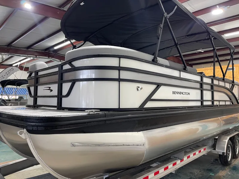 Slide: The Image of 2025 Bennington 25SSRSE pontoon boat with black canopy in indoor showroom. - 6
