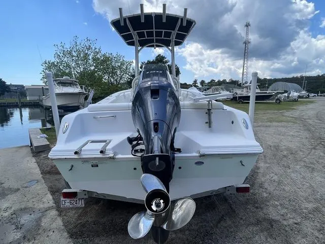 Slide: The Image of 2015 Sportsman Heritage 211 boat with outboard motor, parked on a gravel lot near water. - 5