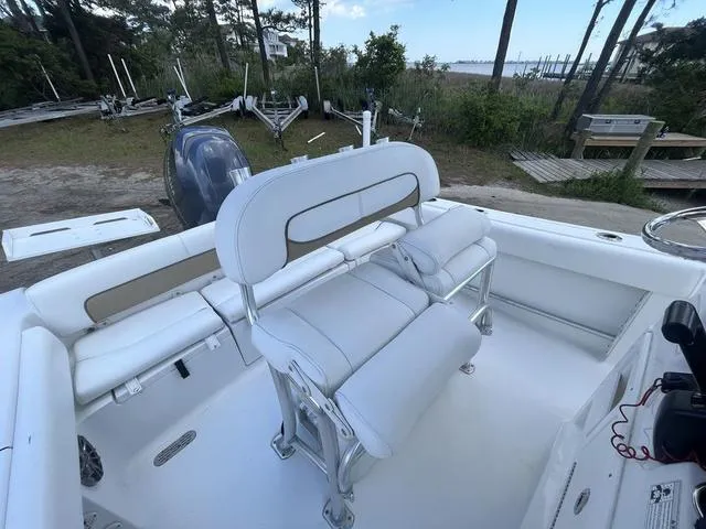 Slide: The Image of 2015 Sportsman Heritage 211 boat interior with white seating and console, docked near trees. - 10