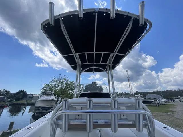 Slide: The Image of 2015 Sportsman Heritage 211 boat with T-top, docked under a partly cloudy sky. - 12