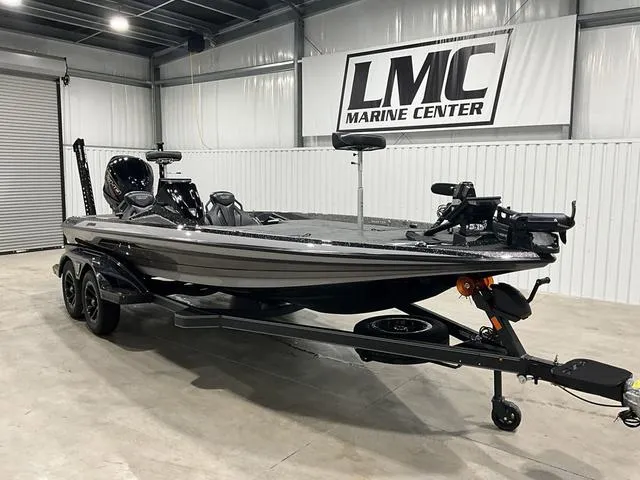 Slide: The Image of 2025 Skeeter FXR21L bass boat in showroom, sleek design, dual-axle trailer. - 6