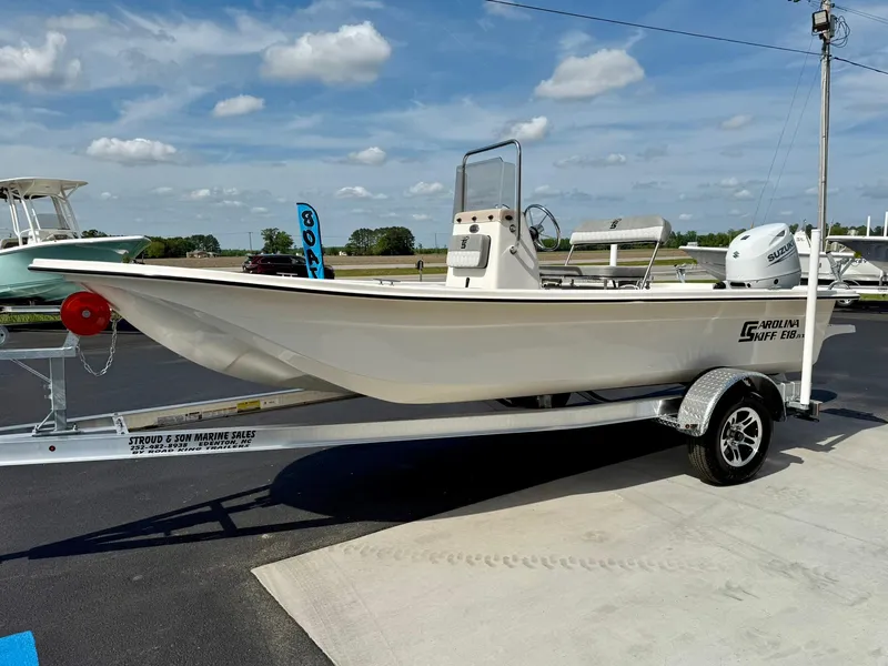 Slide: The Image of 2025 Carolina Skiff E18 JVX CC boat on trailer, parked outdoors under a blue sky. - 34