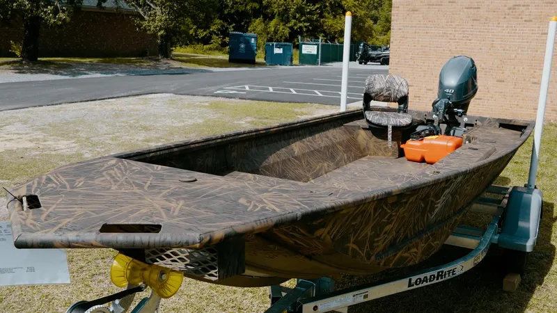 Slide: The Image of 2025 G3 Gator Tough 16 DK boat on trailer, camo design, outdoor setting. - 2