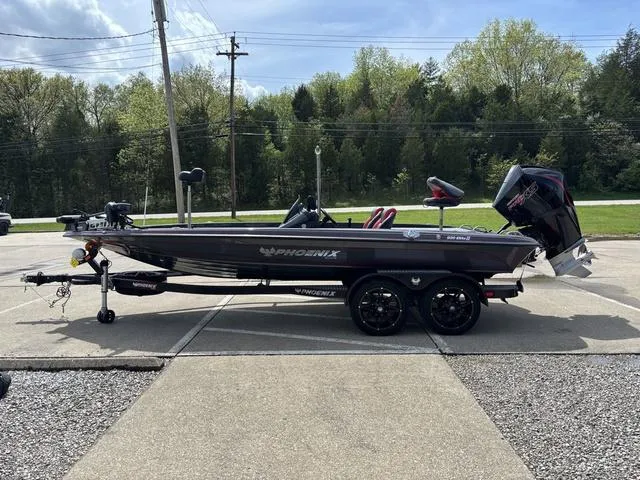 Slide: The Image of 2023 Phoenix 920 Elite II boat on trailer, parked outdoors with trees in background. - 15
