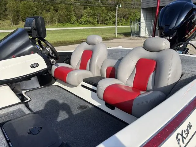 Slide: The Image of 2011 Skeeter FX21 boat interior with red and gray seats, steering console, and motor. - 10