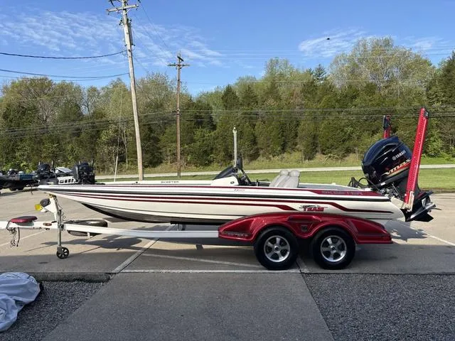 Slide: The Image of 2011 Skeeter FX21 boat on trailer, parked outdoors with trees in background. - 13