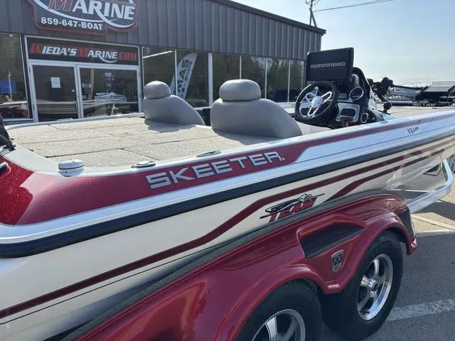 Slide: The Image of 2011 Skeeter FX21 boat with red and white design, parked outside a marine shop. - 3