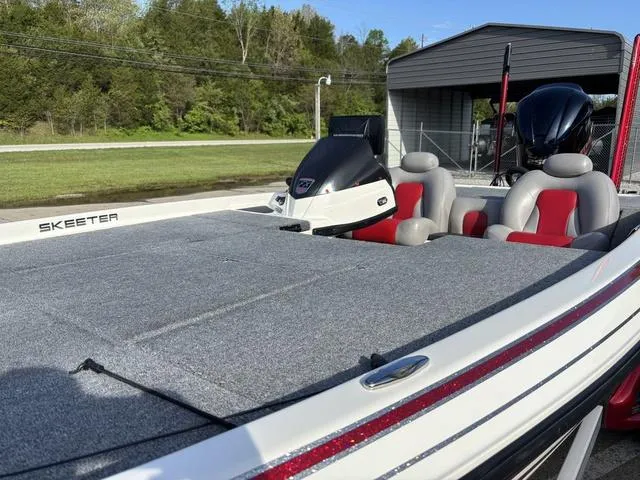Slide: The Image of 2011 Skeeter FX21 boat with gray deck, red seats, and outboard motor in a scenic setting. - 9