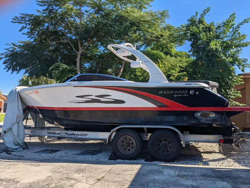 Slide: The Image of 2014 Four Winns H230SS boat on trailer, parked outdoors under trees. - 2