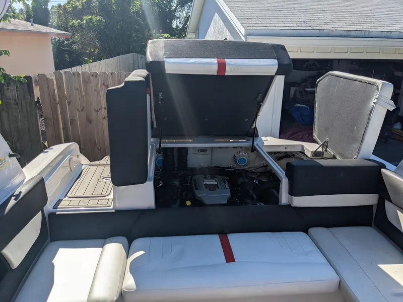 Slide: The Image of 2014 Four Winns H230SS boat interior with open engine compartment, showcasing seating and storage. - 3