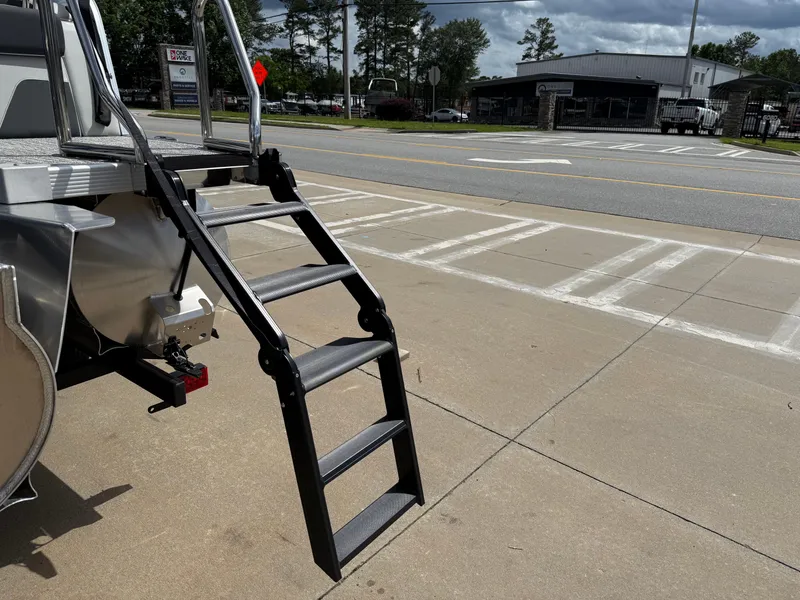 Slide: The Image of Sturdy metal steps on 2025 Avalon LSZ Quad Lounger Shift boat, parked on concrete. - 12