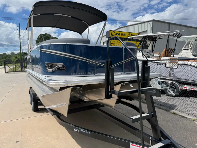 Slide: The Image of 2025 Avalon LSZ Quad Lounger Shift boat on trailer, blue exterior, parked outdoors. - 4