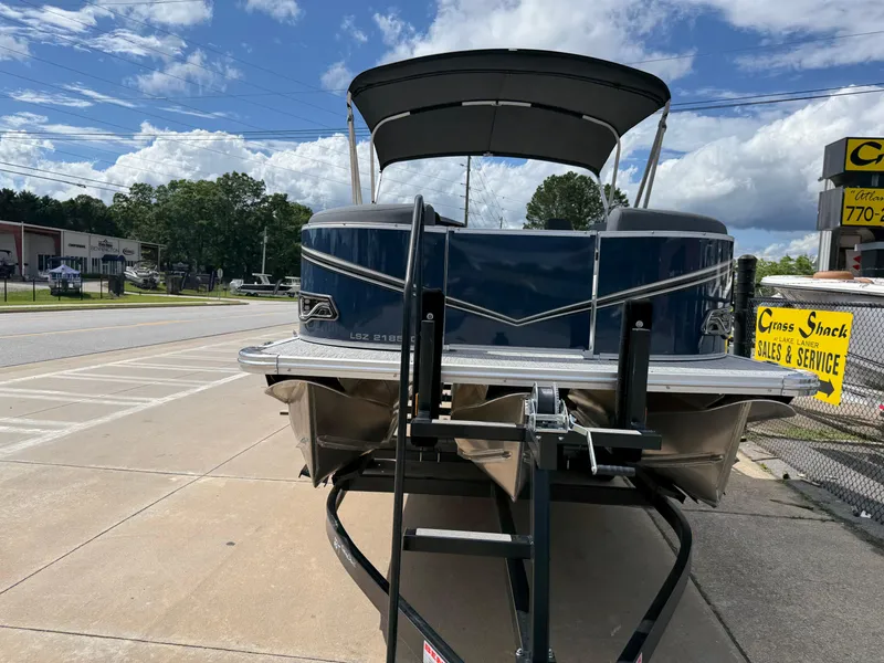 Slide: The Image of 2025 Avalon LSZ Quad Lounger Shift pontoon boat on trailer, parked outdoors. - 5