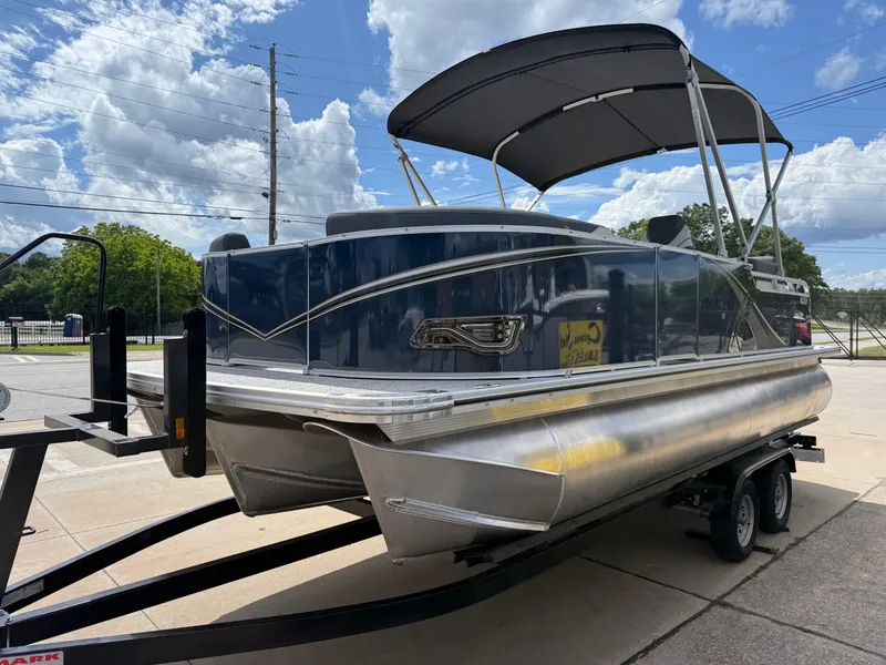 Slide: The Image of 2025 Avalon LSZ Quad Lounger Shift pontoon boat on trailer under cloudy sky. - 7