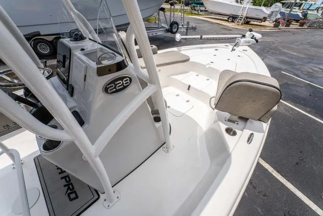 Slide: The Image of 2023 Sea Pro 228 Bay boat interior with seating and console, parked outdoors. - 16