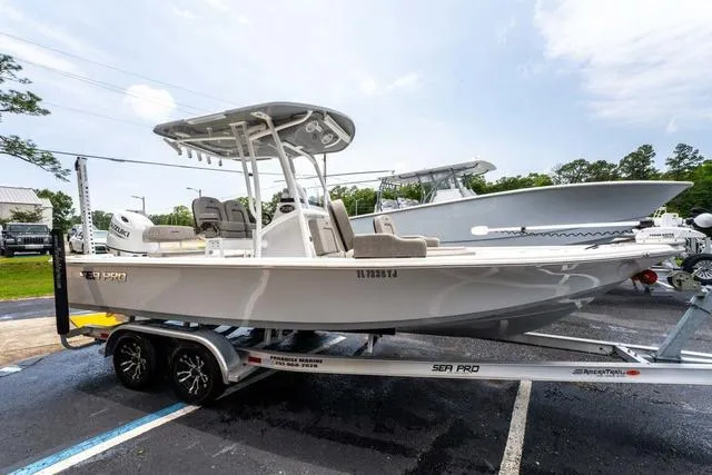 Slide: The Image of 2023 Sea Pro 228 Bay boat on trailer, parked in a lot under a cloudy sky. - 6