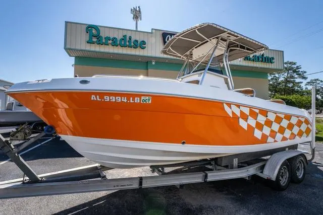 Slide: The Image of 2004 Cobia 234 boat with orange checkered design on trailer, parked outside Paradise Marine. - 1