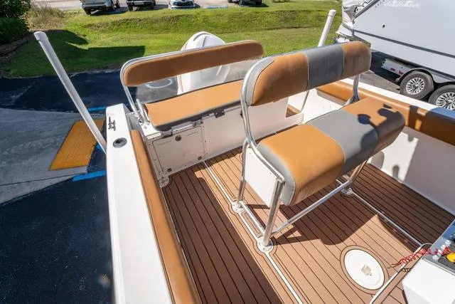 Slide: The Image of 2004 Cobia 234 boat interior with tan seating and wood-style flooring. - 10