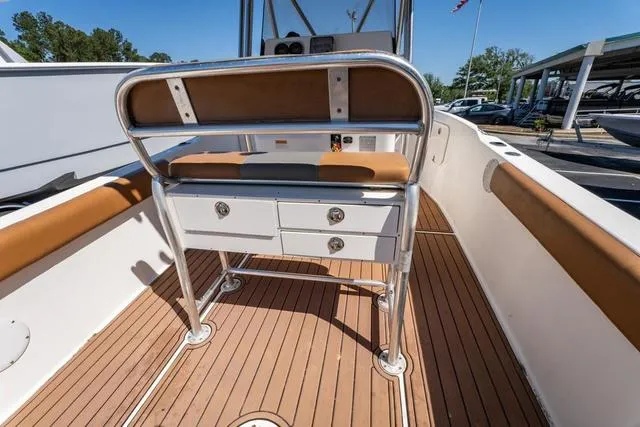 Slide: The Image of 2004 Cobia 234 boat interior with cushioned seating and storage drawers on teak flooring. - 12