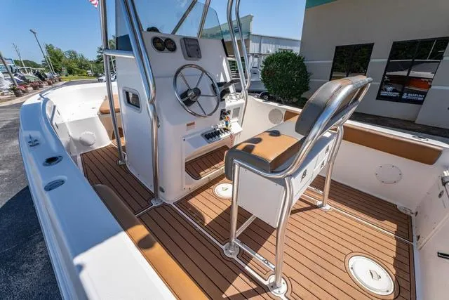 Slide: The Image of 2004 Cobia 234 boat interior with helm, seating, and teak flooring. - 13