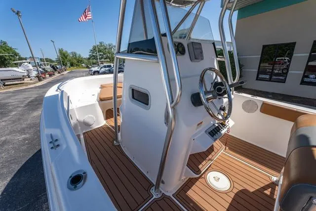 Slide: The Image of 2004 Cobia 234 boat interior with steering wheel, teak flooring, and American flag in background. - 14