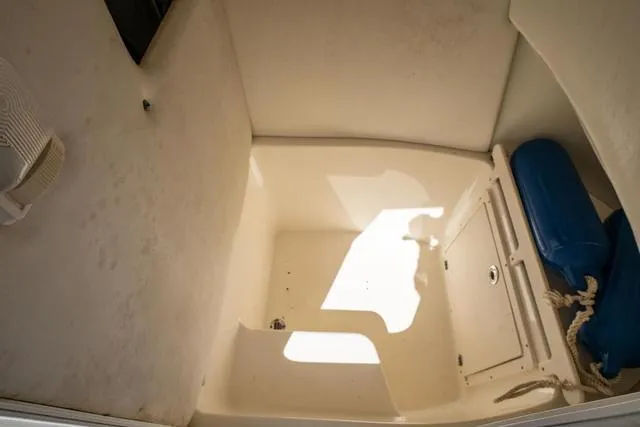 Slide: The Image of Interior of a 2004 Cobia 234 boat, featuring storage space and blue cushions. - 19