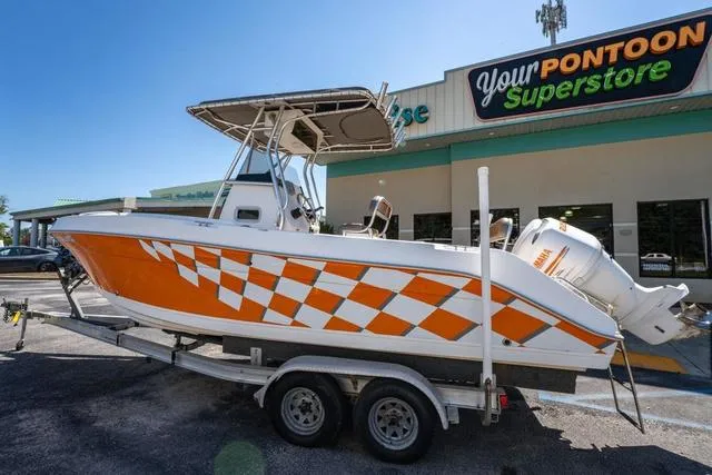 Slide: The Image of 2004 Cobia 234 boat with orange checkered design on trailer at a pontoon superstore. - 2