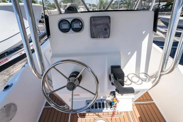 Slide: The Image of 2004 Cobia 234 boat console with steering wheel and gauges, featuring wood-style flooring. - 20