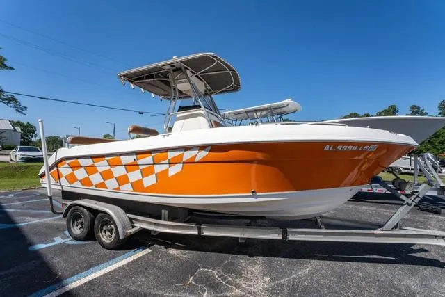 Slide: The Image of 2004 Cobia 234 boat with orange checkered design on trailer, parked outdoors. - 6