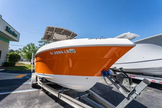 Slide: The Image of 2004 Cobia 234 boat with orange hull on trailer, parked outdoors. - 7